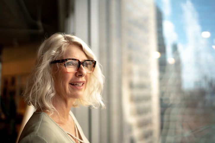 smiling woman looking out of the window of an office block