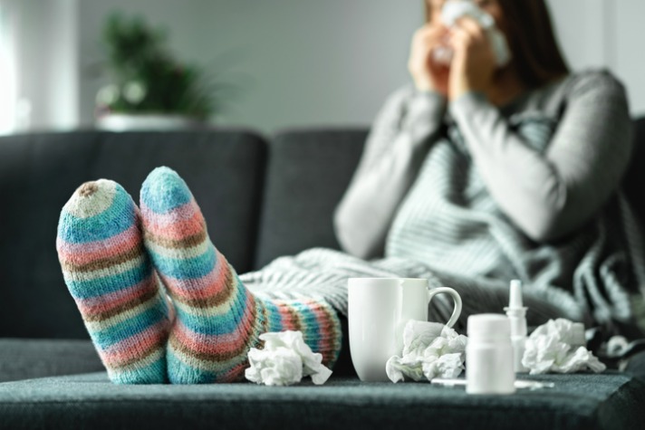 What’s different about this year’s ‘flu season in Australia? - woman with the flu on the couch blowing her nose