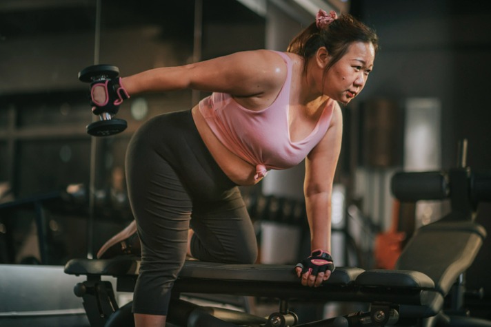 Getting back into shape after a break image of a larger Asian lady lifting weights at the gym